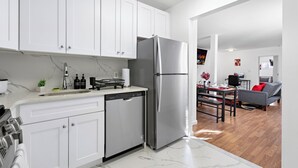 Una cocina moderna con armarios blancos, un refrigerador de acero inoxidable y un lavavajillas.