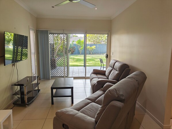A living room with a sofa, a TV, and a sliding glass door leading to a backyard.