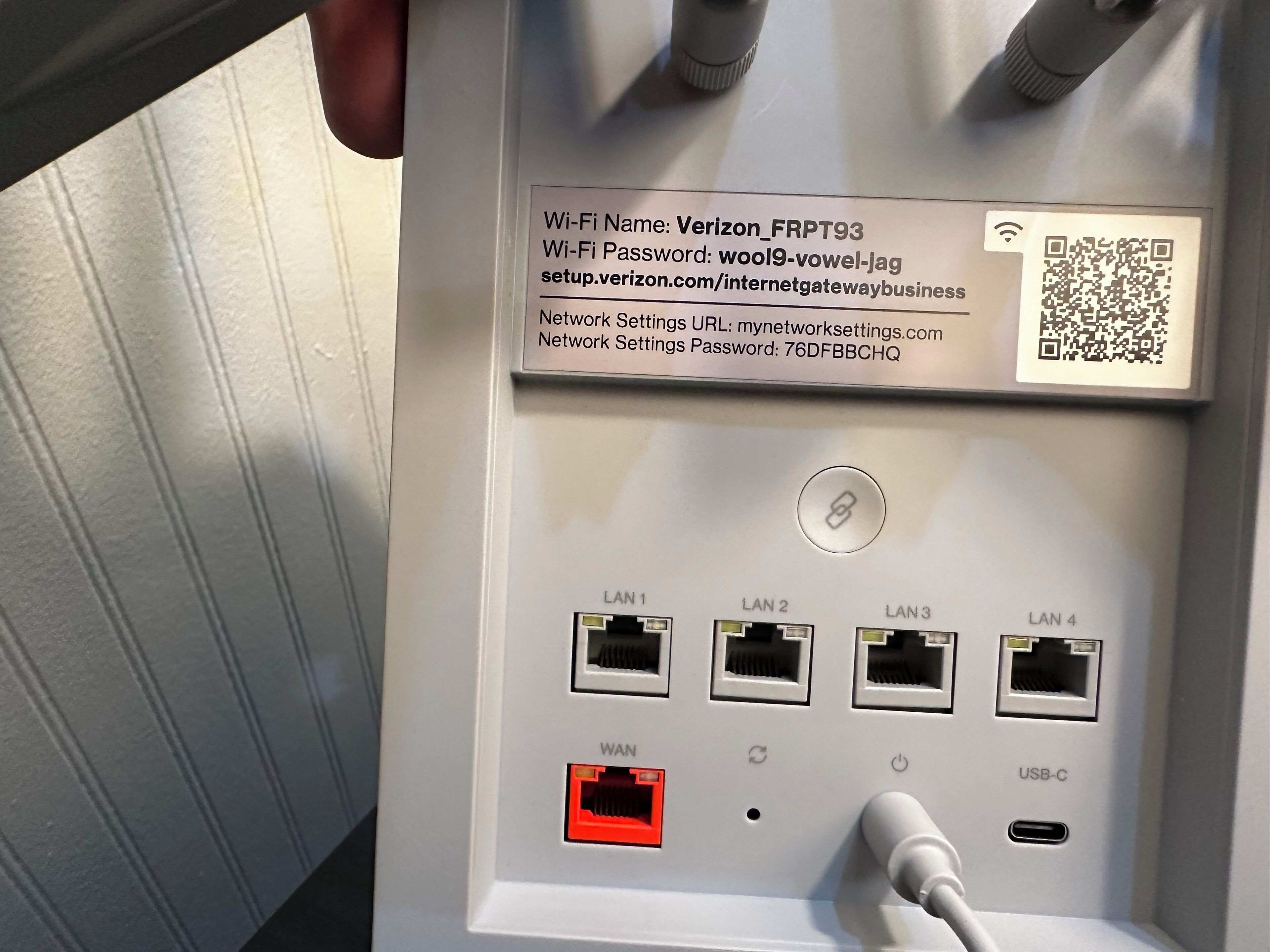 Ein Netzwerkgerät mit beschrifteten Anschlüssen für LAN- und WAN-Verbindungen, einem QR-Code und einem USB-C-Anschluss.