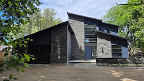 Ein modernes, zweistöckiges Gebäude mit Naturstein-Fassade, großen Fenstern und einer überdachten Garage.