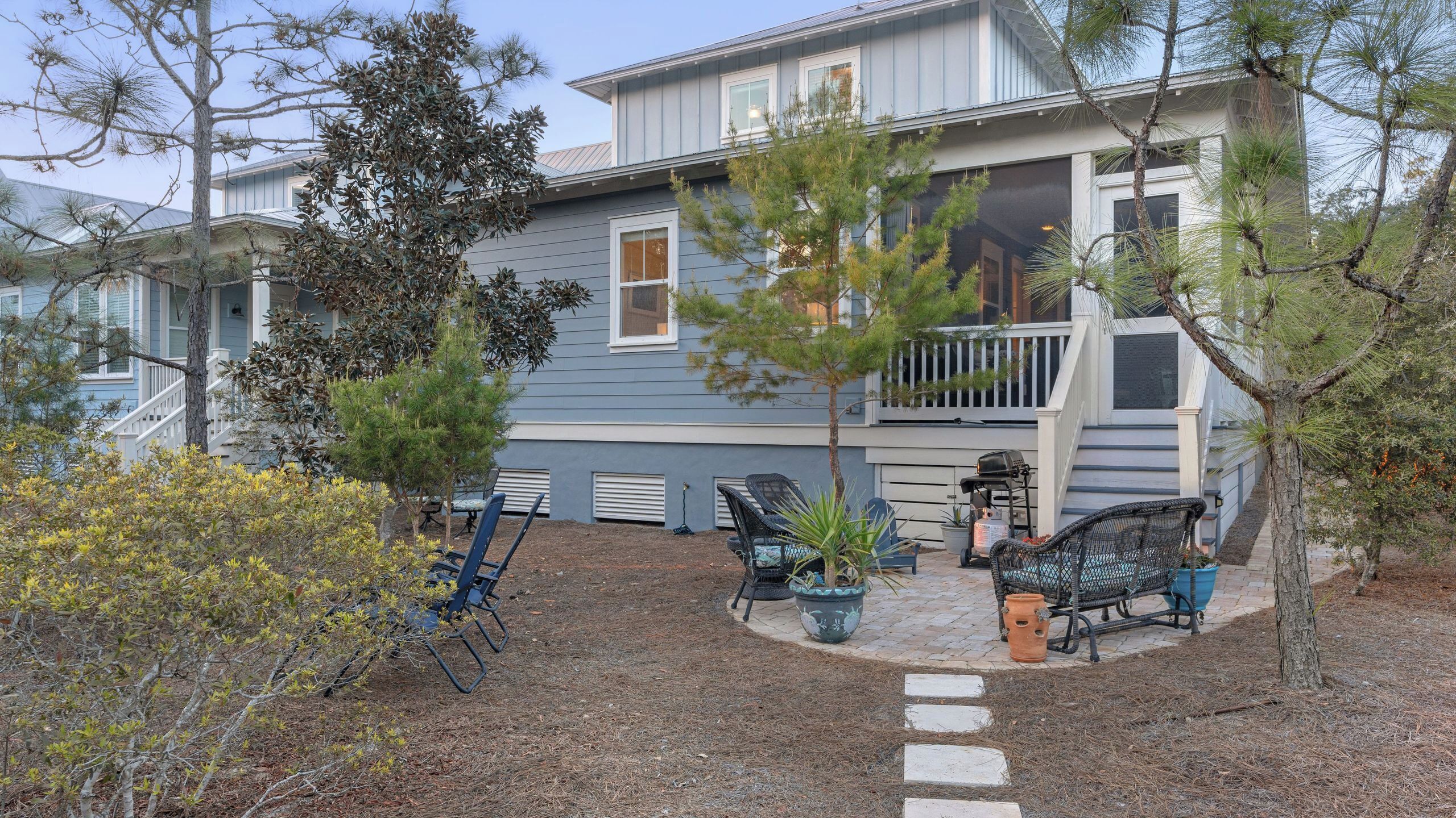 A two-story house with a porch, outdoor seating, and a small garden.
