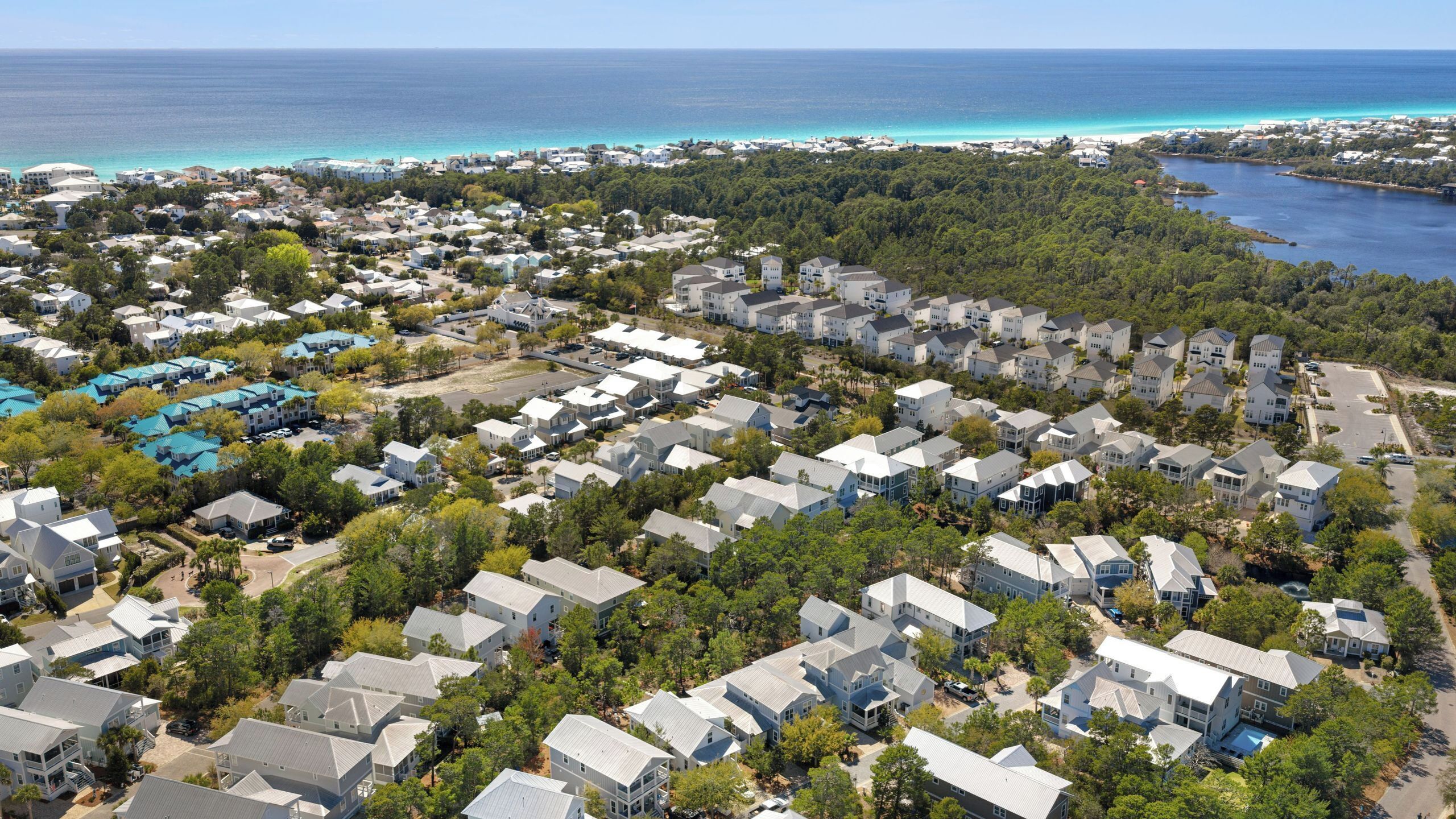 An aerial view of a residential area with houses, trees, and a coastline.
