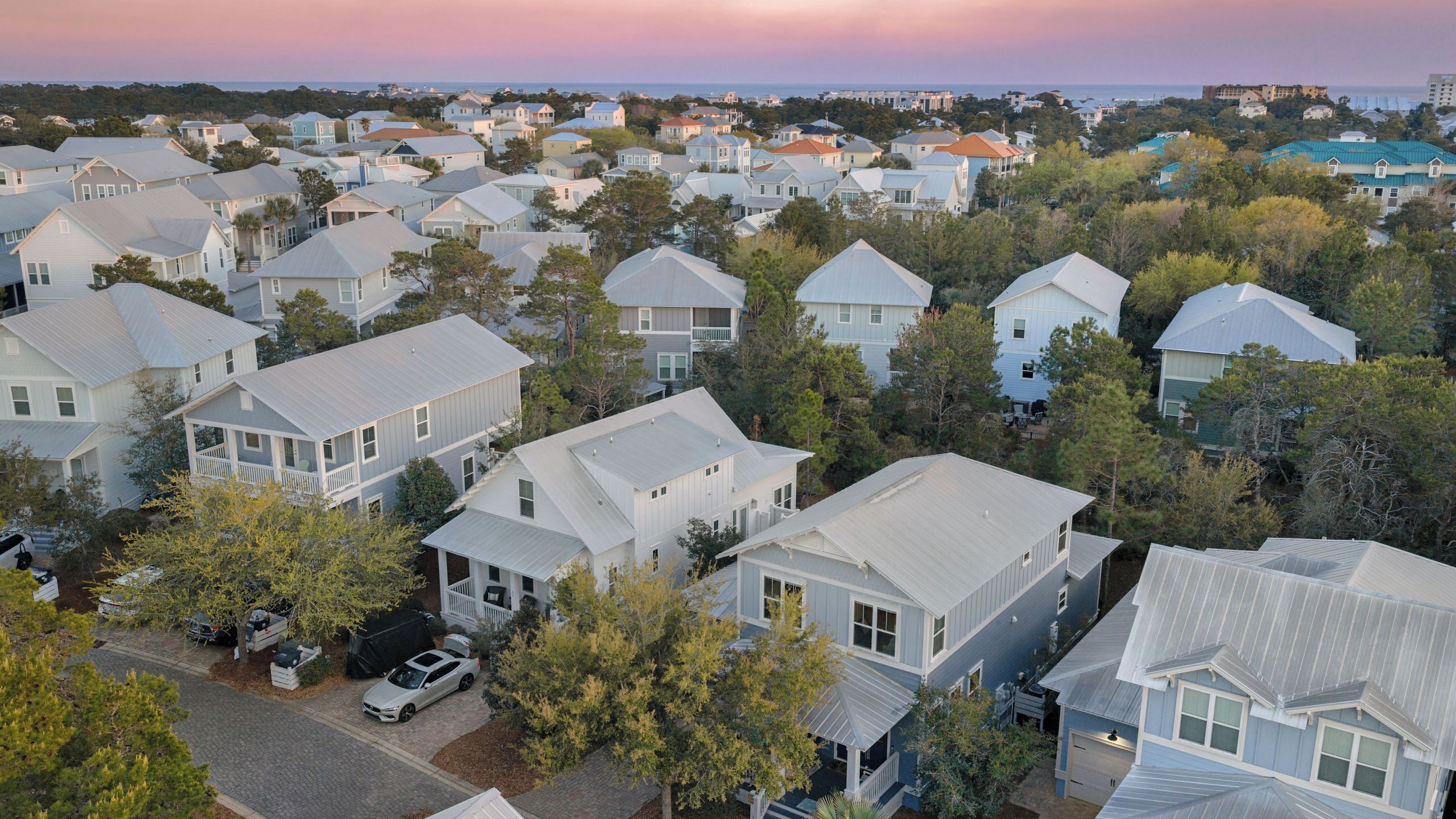 A residential area with multiple houses, a paved driveway, and a parked car.