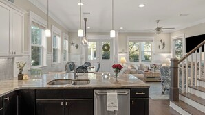 A spacious kitchen with a large island, dark cabinetry, and a view to the living area. - Three Times The Fun by Avantstay Blue Mountain Pool + Pet-friendly (Santa Rosa Beach)
