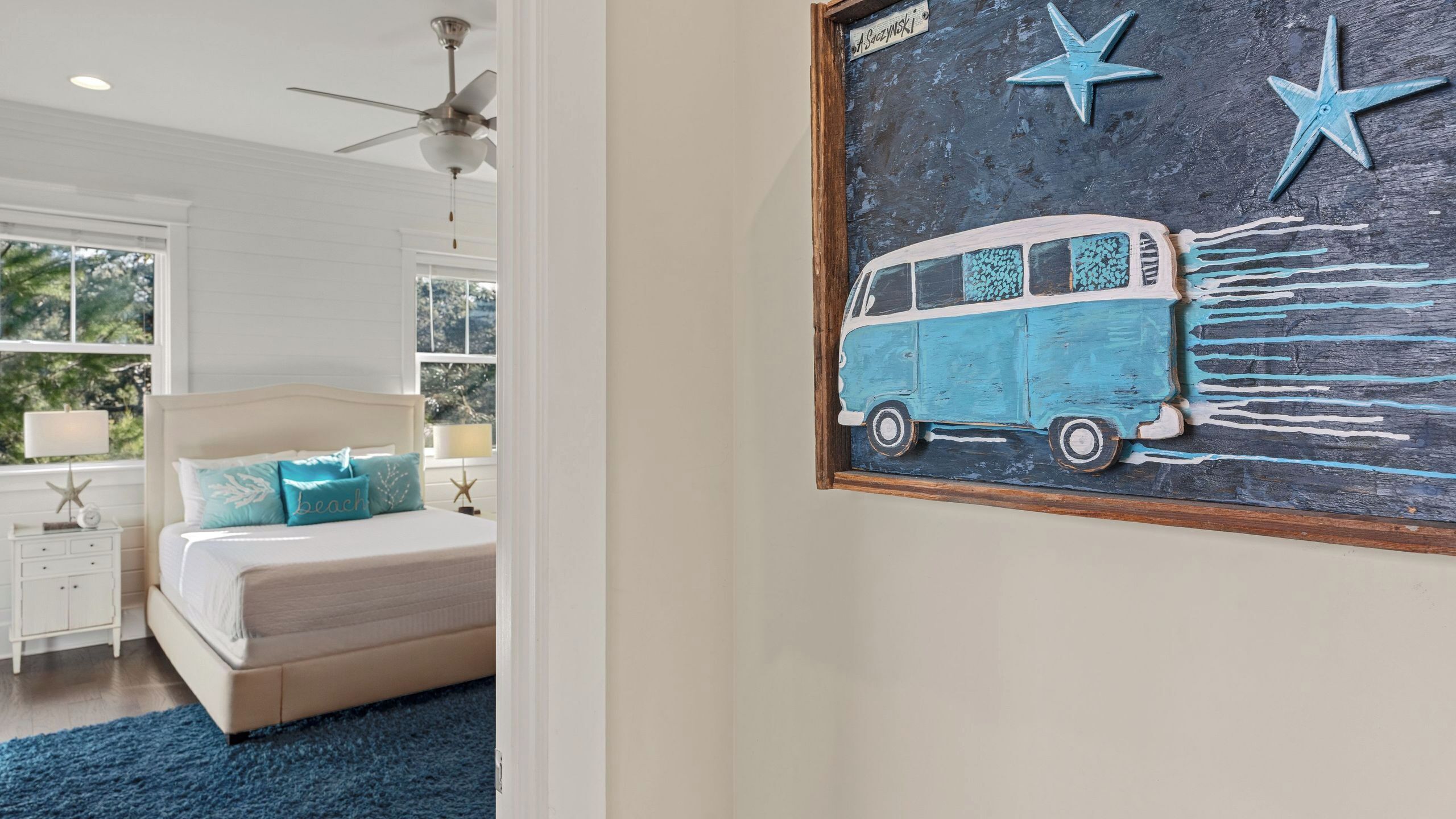 A bedroom with a bed, nightstands, a ceiling fan, and a window with a view of trees.