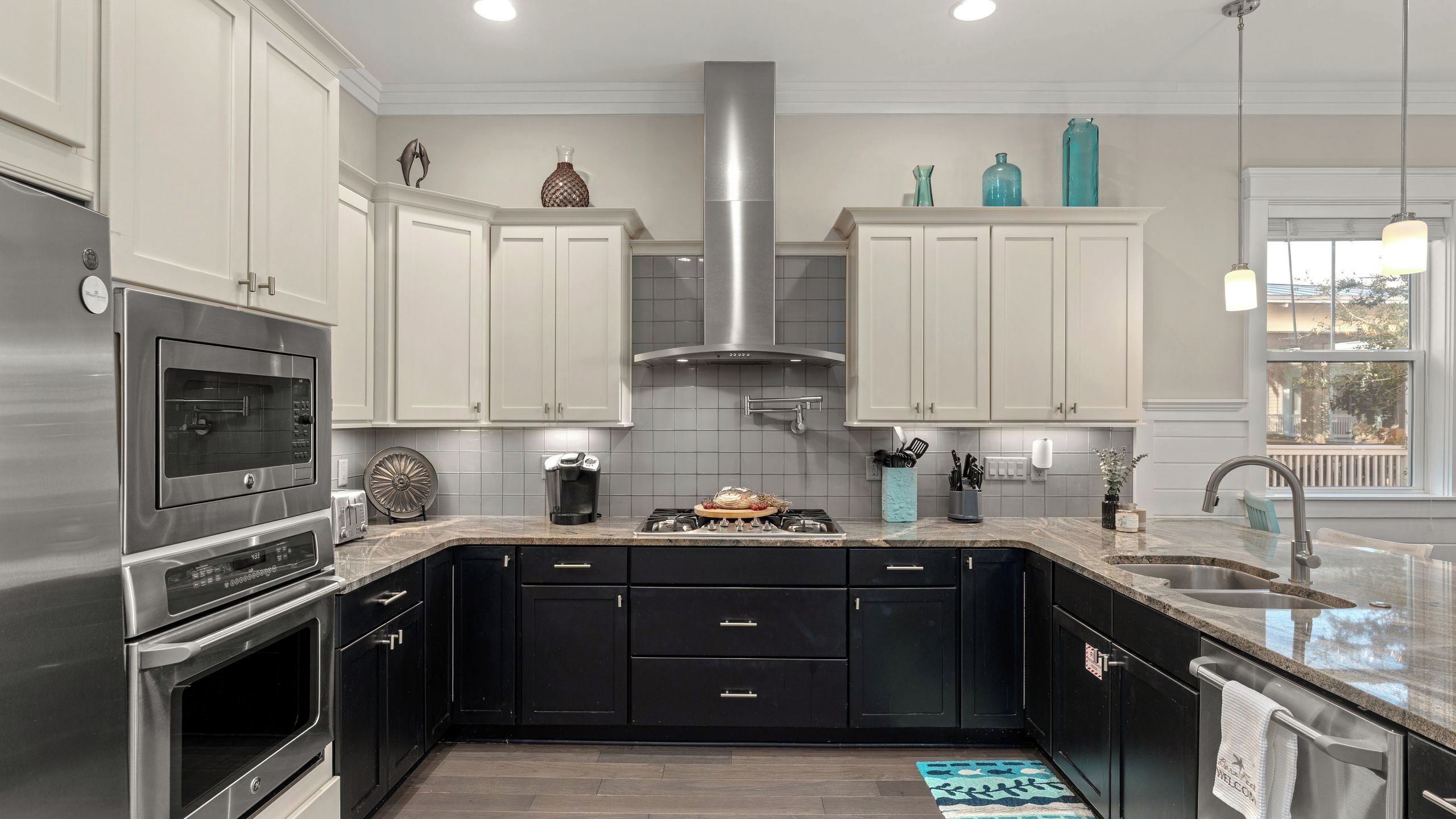 A modern kitchen with stainless steel appliances, black cabinetry, and a large island.