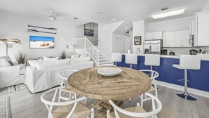 A modern apartment with a living room, dining area, and kitchen. - All Decked Out by Avantstay Pool & Private Beach Access, Bikes Provided (Panama City Beach)