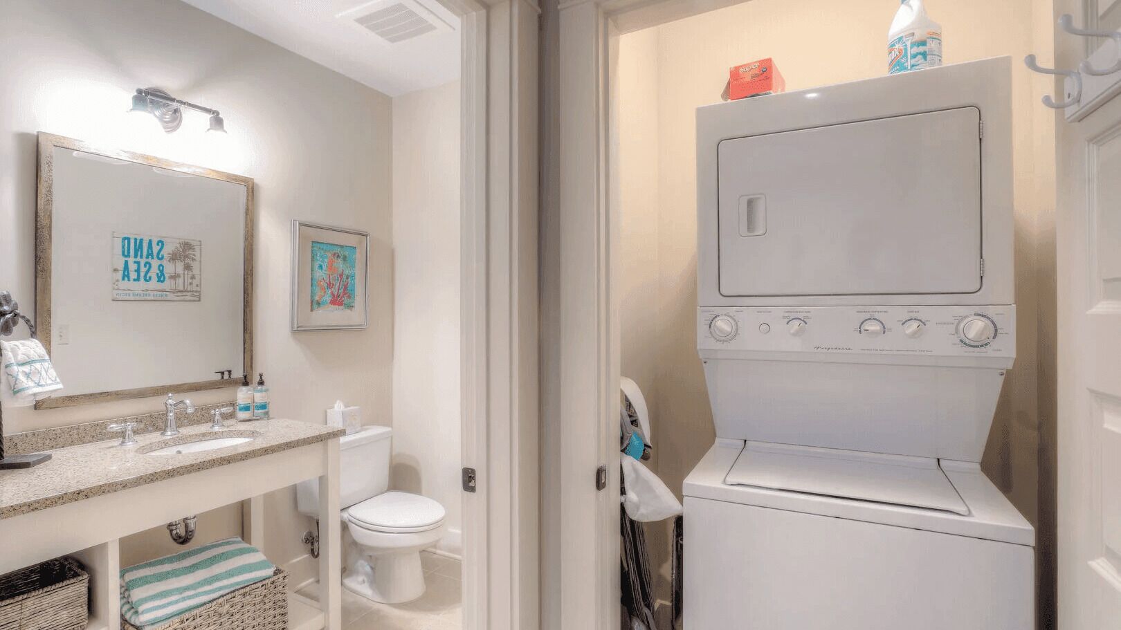 A bathroom with a sink, mirror, toilet, and a washing machine.