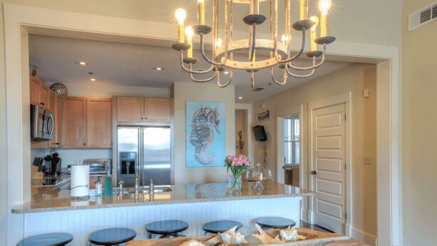 A modern kitchen with a central island, stainless steel appliances, and a chandelier. - Smurf Mountain by Avantstay Private Beach + Pool Redfish Village (Santa Rosa Beach)