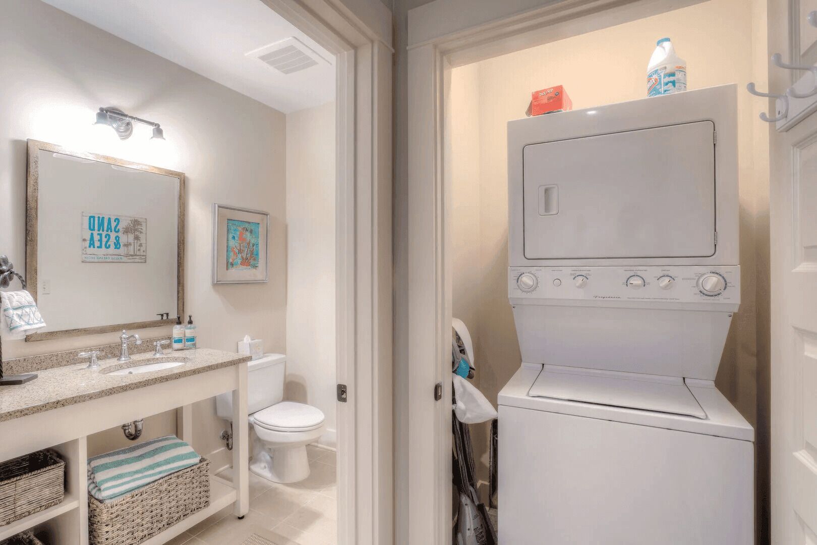 A compact bathroom with a sink, mirror, toilet, and a front-loading washing machine.