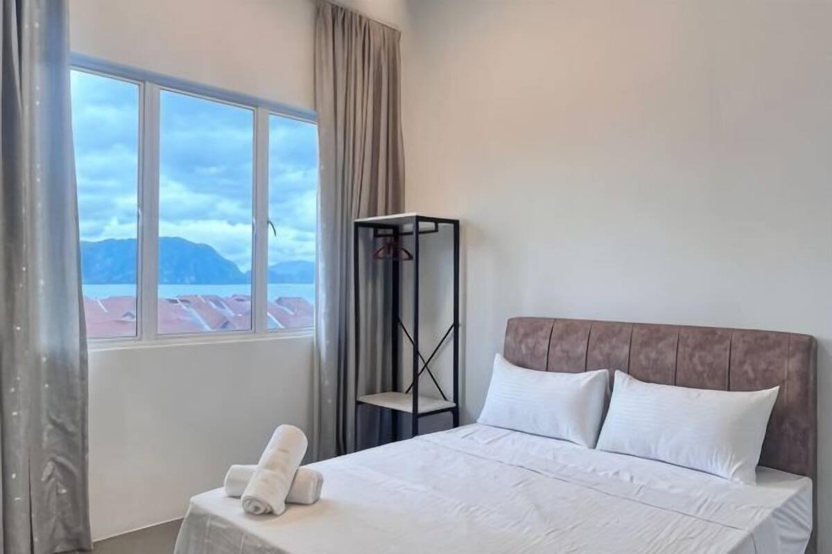 Une chambre d’hôtel avec un lit, une fenêtre avec des rideaux, une table de chevet et une vue sur les montagnes.