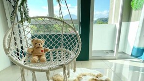 A room with a wicker chair, a teddy bear, and a fluffy rug. - The Cube Langkawi (Langkawi)