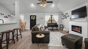 Una sala de estar moderna con chimenea, ventilador de techo y televisor de pantalla plana.