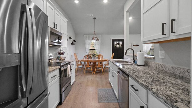 Una cocina moderna con electrodomésticos de acero inoxidable, armarios blancos y una mesa de comedor de madera.