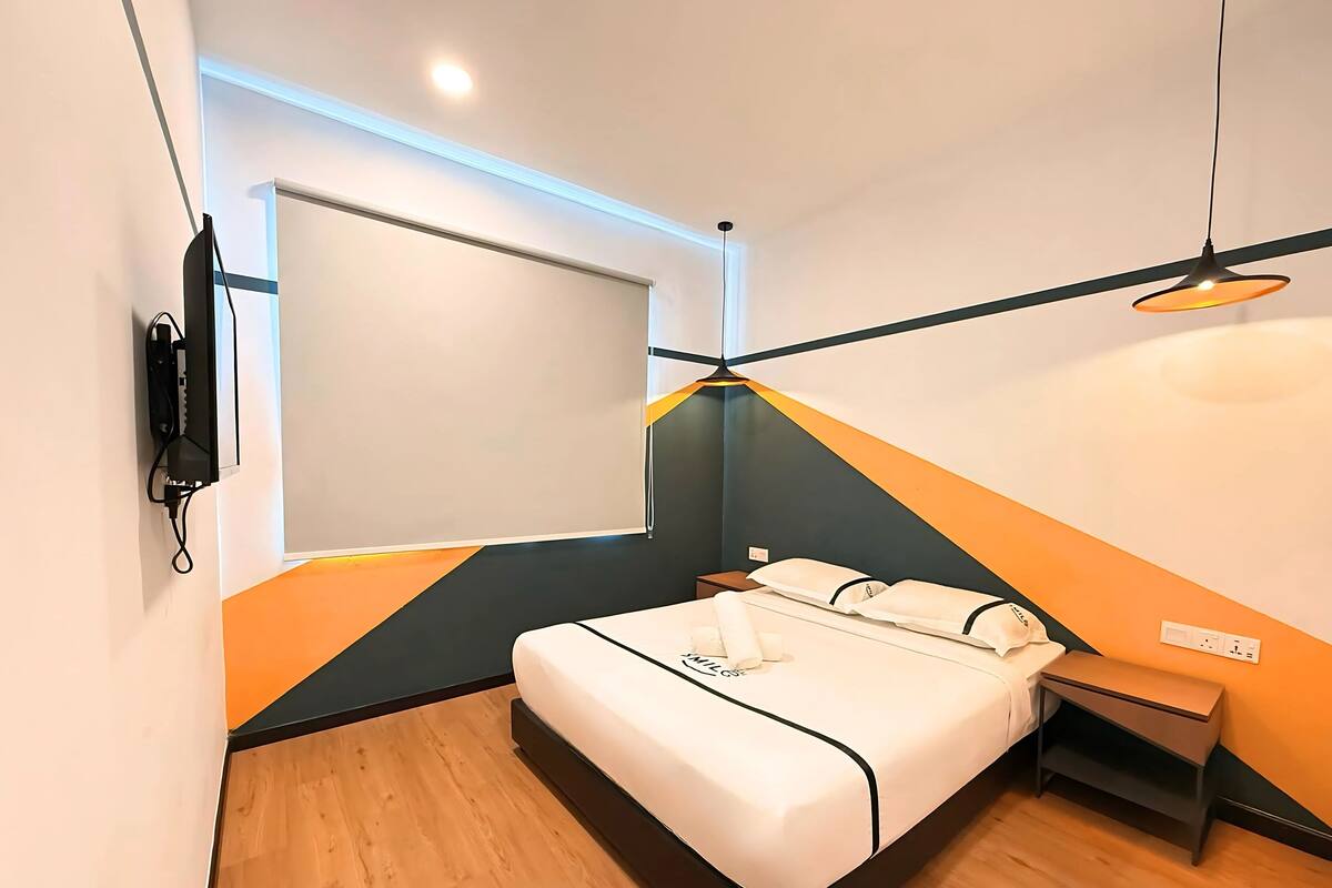 A modern hotel room with a bed, bedside table, and a TV mounted on the wall.