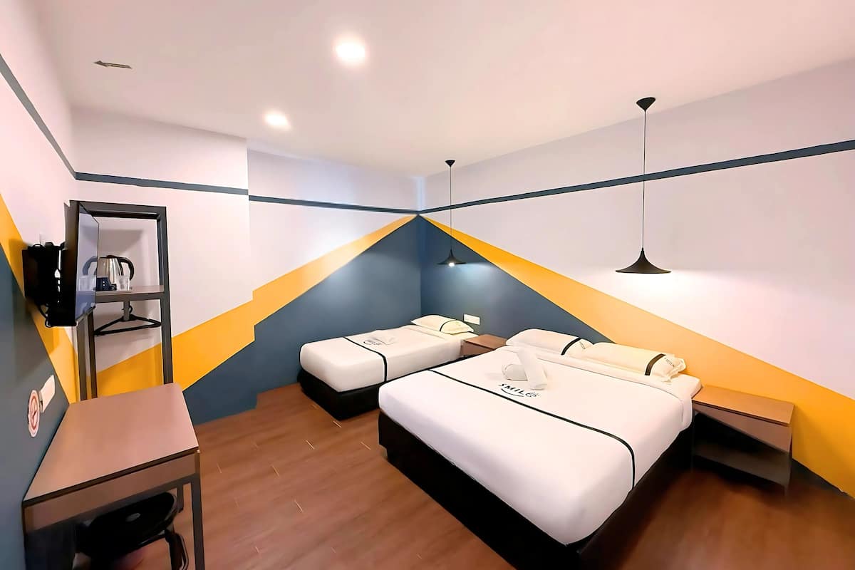 A modern hotel room with two beds, a desk, a mirror, and a shelf with toiletries.