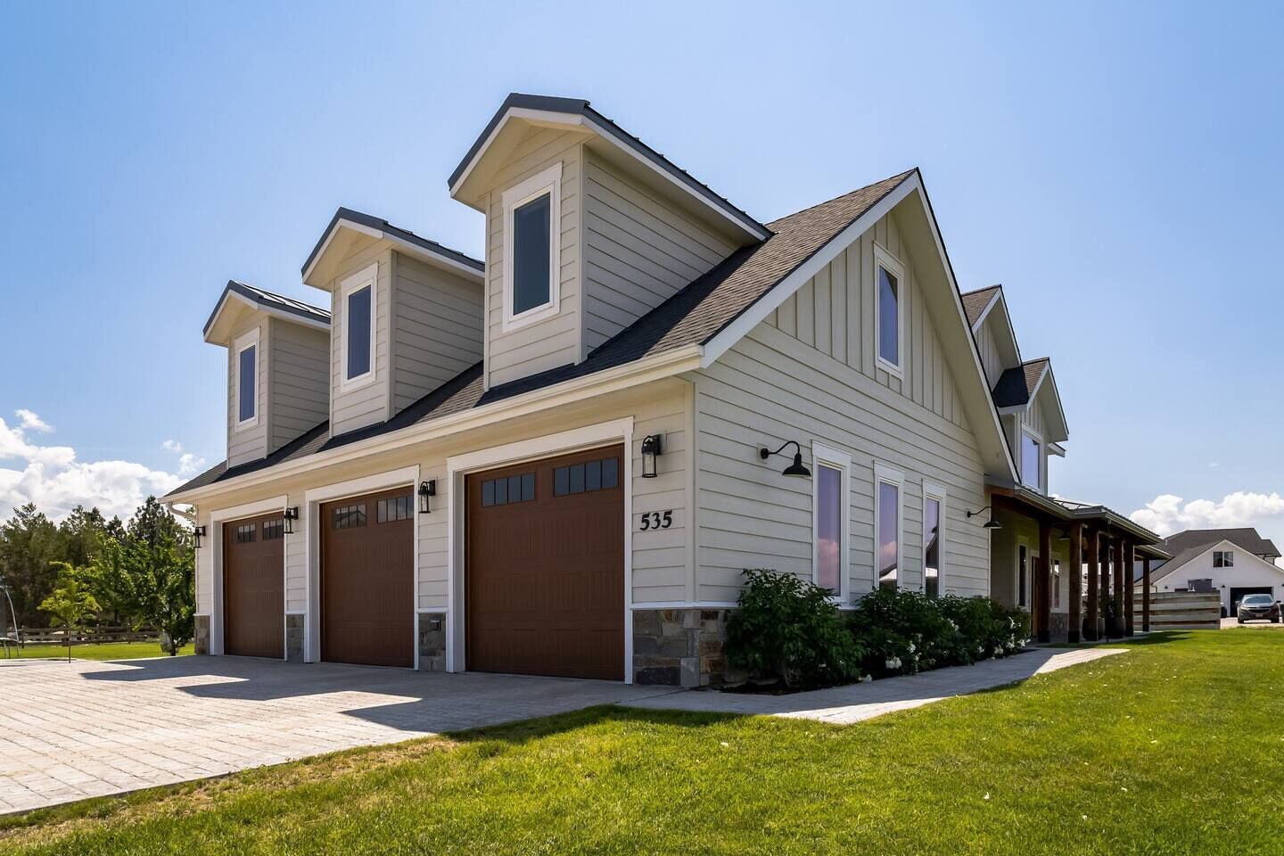 A two-story house with a garage, a covered porch, and a well-maintained lawn.