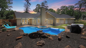 Ein Haus mit Swimmingpool, Sitzgelegenheiten im Freien und einem gepflegten Garten.