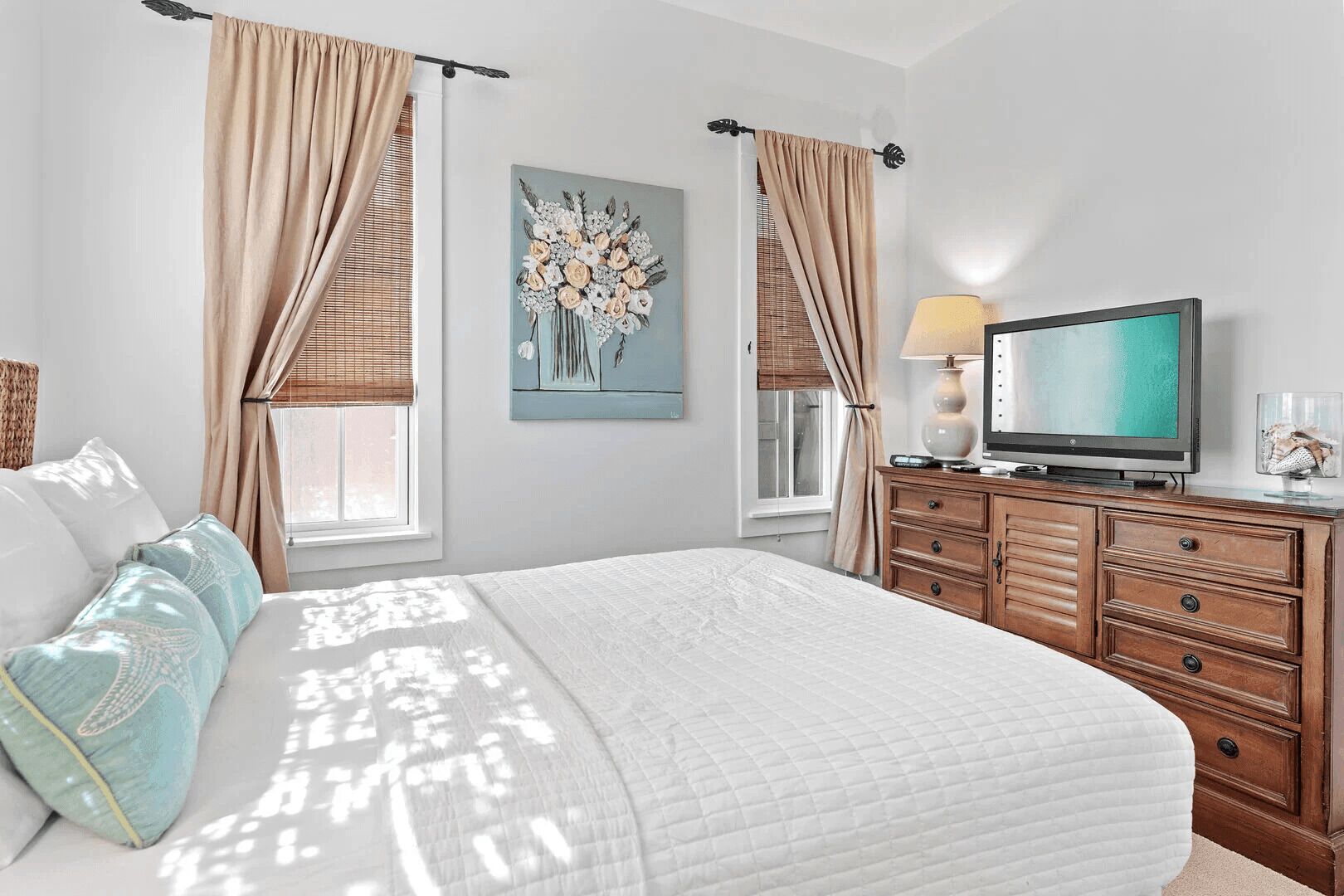 Une chambre d’hôtel avec un grand lit, une télévision, une commode et un tableau au mur.