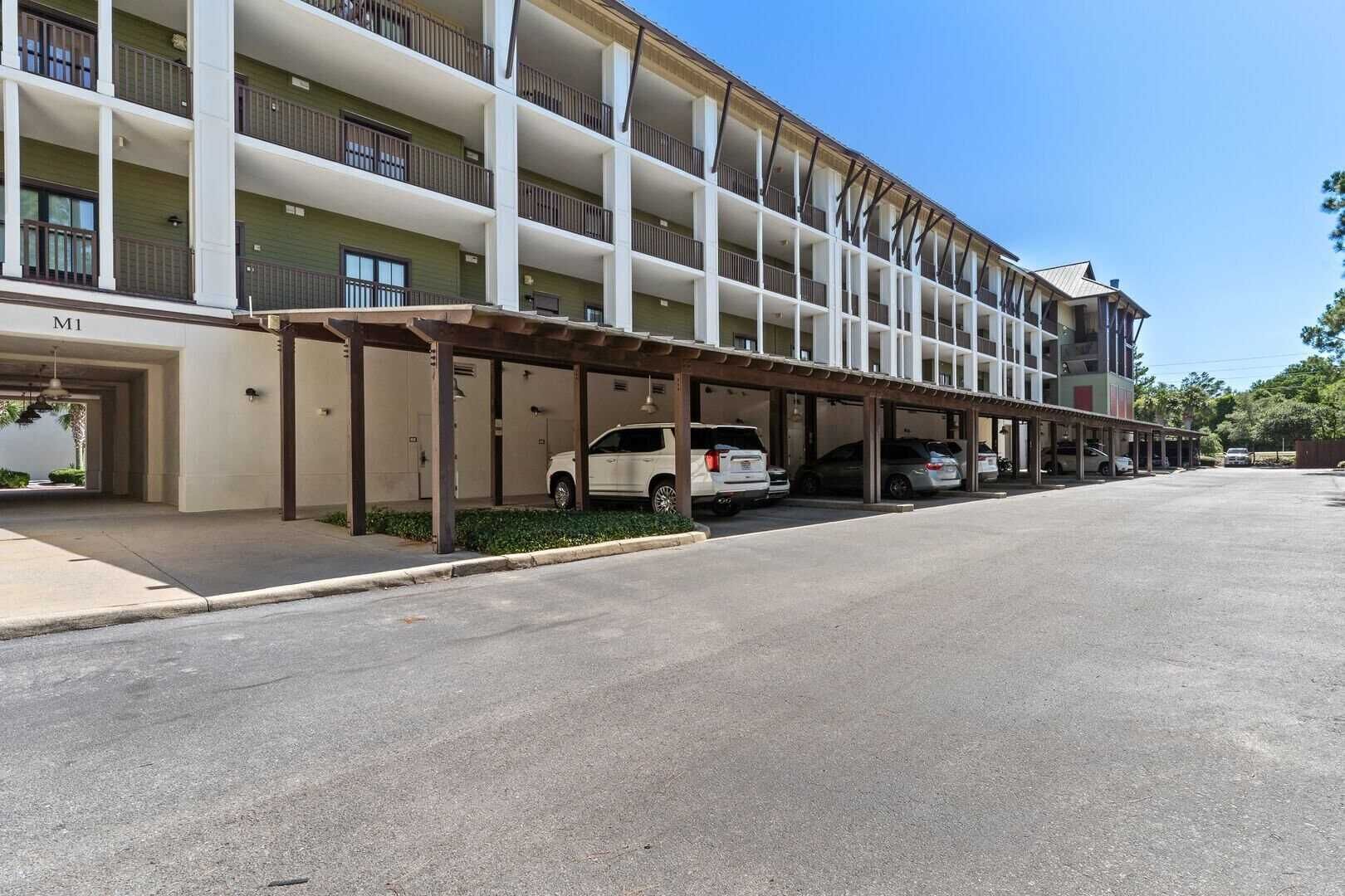 A multi-story hotel with a covered parking area and several cars parked.