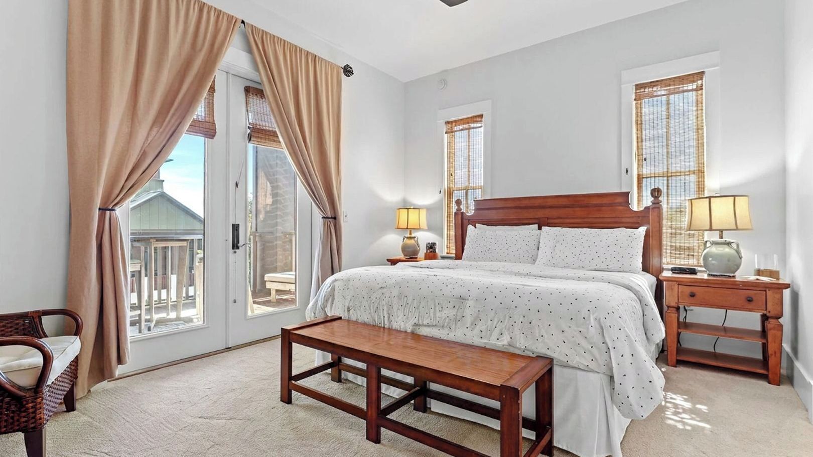 A bedroom with a bed, bedside tables, a bench, and a view through a door.