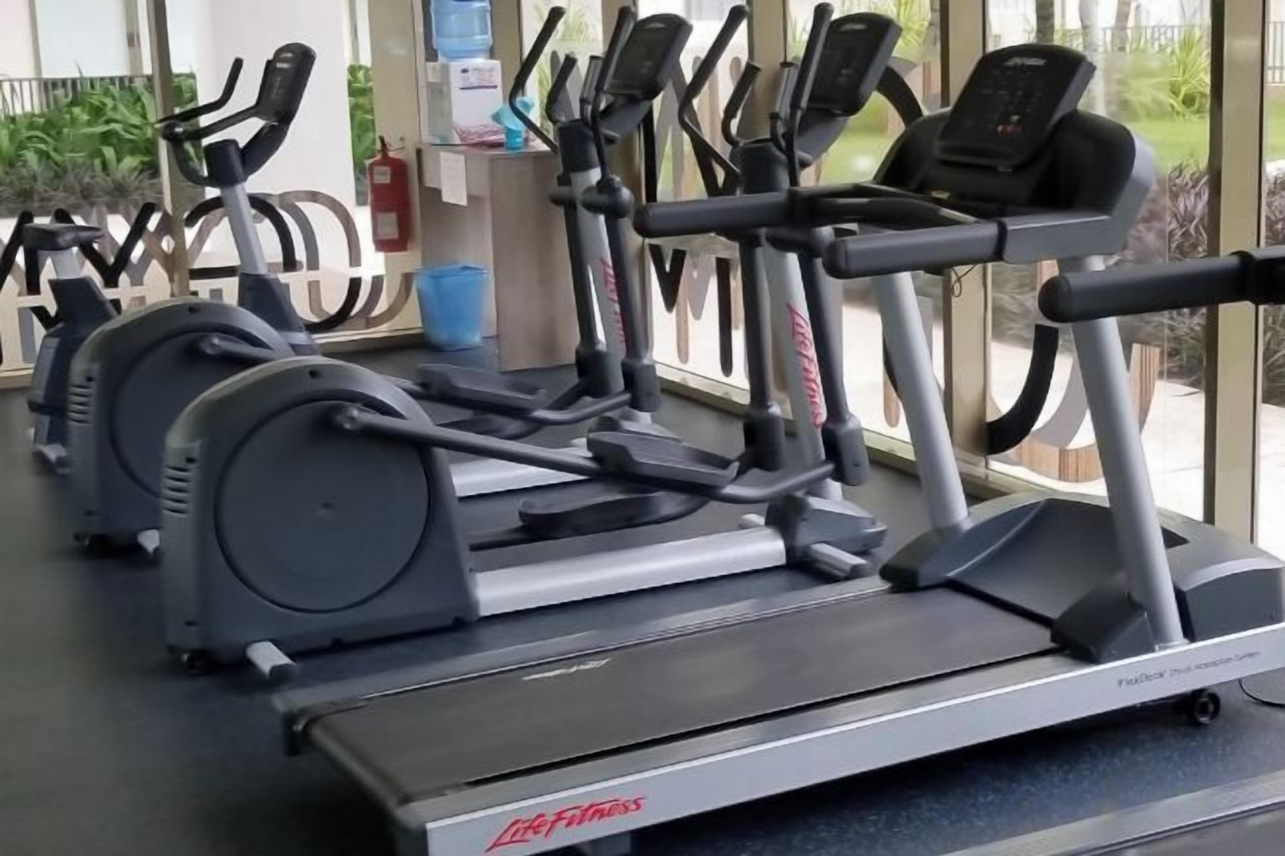 A row of stationary bikes and treadmills in a gym.