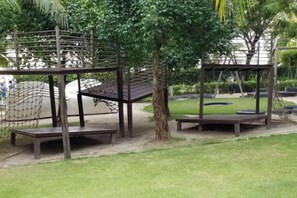 Une aire de jeux avec des balançoires, une structure d’escalade et un espace pour s’asseoir.