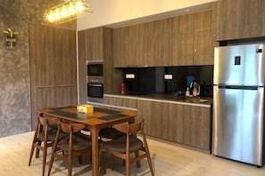Uma cozinha moderna com armários de madeira, uma geladeira de aço inoxidável e uma mesa de jantar com cadeiras.