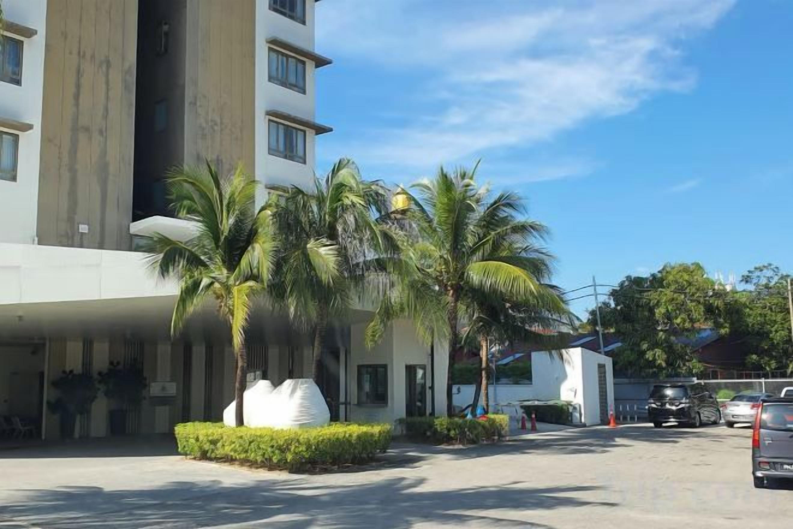 A hotel with a modern design, featuring a multi-story building, palm trees, and a parking area.