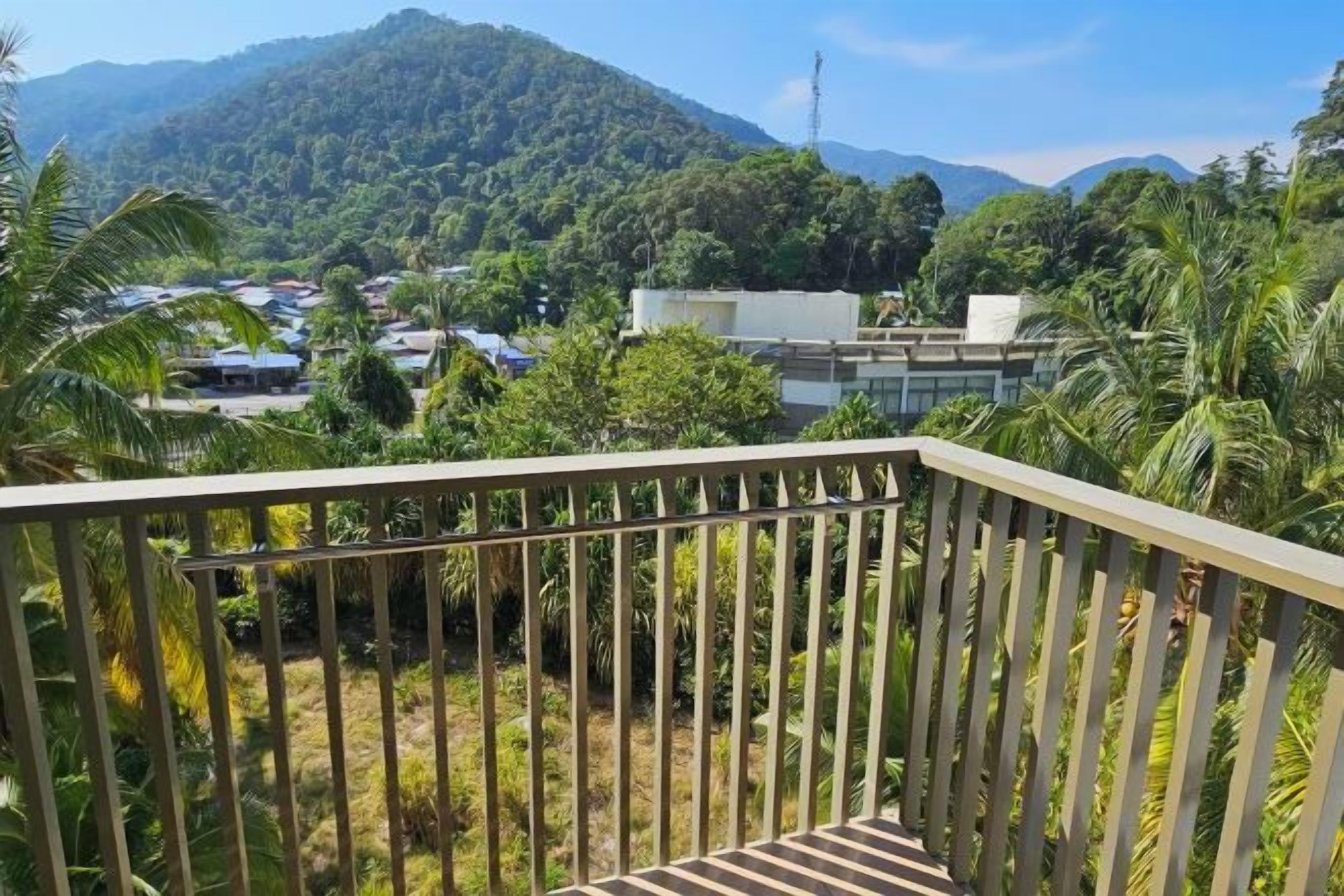 A balcony with a view of a mountainous landscape, a road with vehicles, and some buildings.