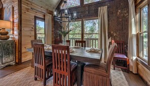 Enjoy meals in this cozy dining area with a large table and six chairs, a stylish chandelier, and wooden paneling.