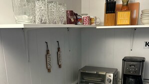 Une cuisine équipée d’un grille-pain, d’une machine à café et de divers ustensiles de cuisine rangés sur des étagères.