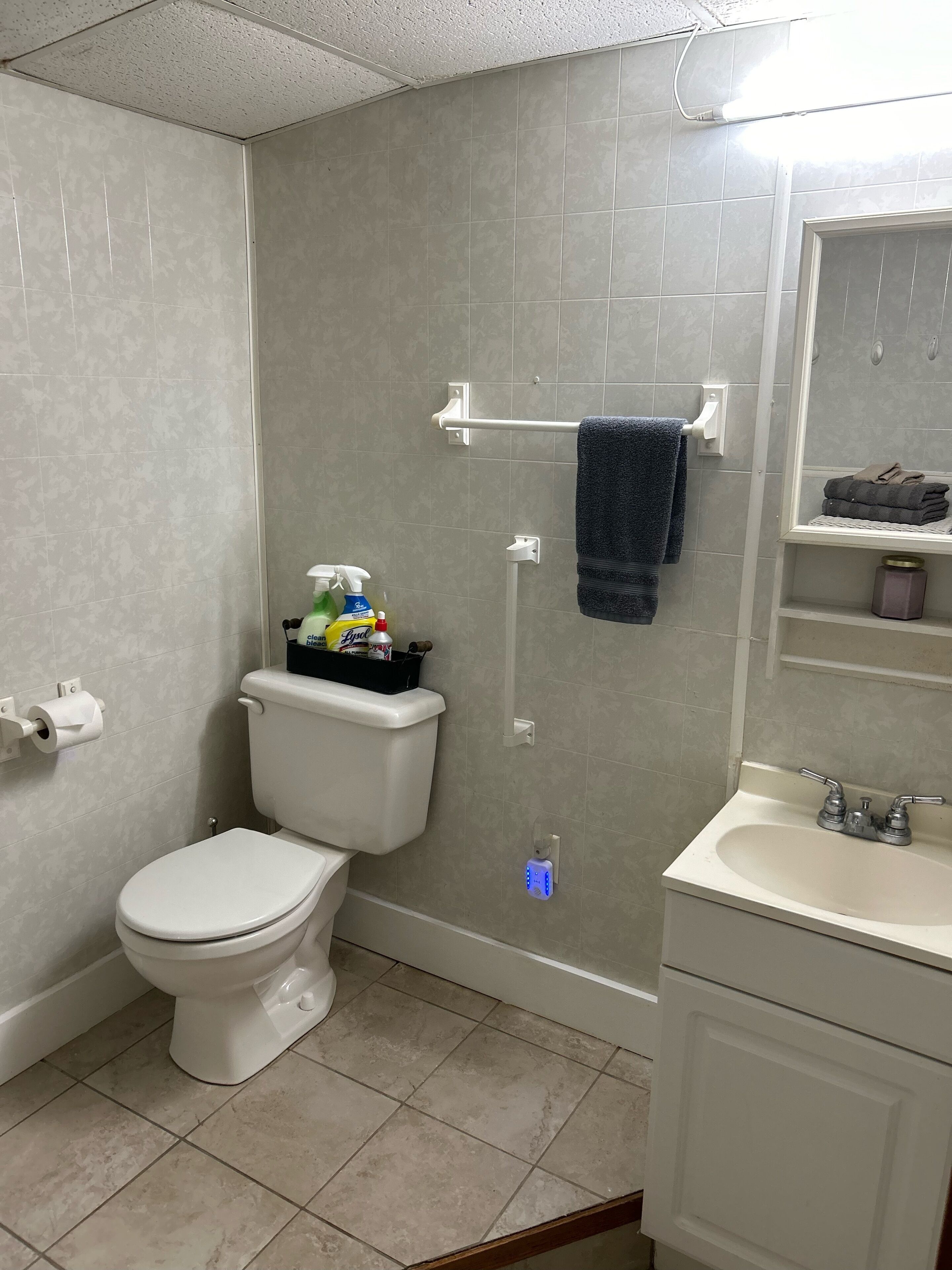 A bathroom with a toilet, a sink, a shower, and a towel rack.
