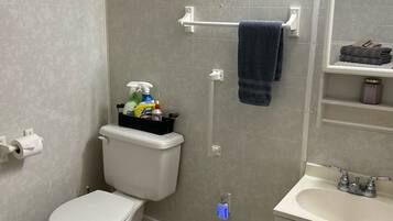 A bathroom with a toilet, a sink, a shower, and a towel rack.