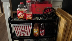Une machine à pop-corn ancienne, avec un dessus rouge et une base noire, accompagnée d’une boîte étiquetée « Pop-corn » et de bouteilles d’assaisonnement pour pop-corn « Orville Redenbacher’s Original ».