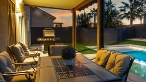 Une terrasse extérieure avec une piscine, un barbecue et des sièges.