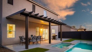 Une maison moderne dotée d’un patio couvert, d’une piscine et d’un espace barbecue.
