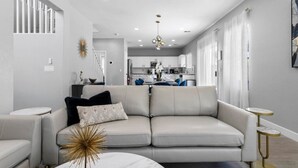 Un salon moderne avec un canapé, une table basse et, au fond, un coin repas.