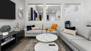 Un salon moderne avec un canapé, une table basse et un téléviseur.