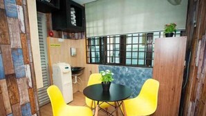 A small room with a round table and four chairs, one red and three yellow. - DJ Citi Inn Premier (Kuala Terengganu)