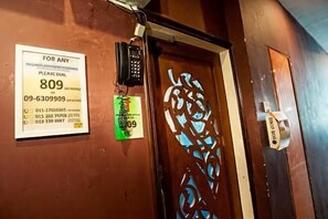 A hotel entrance with a door, a phone, and a sign with emergency contact numbers. - DJ Citi Inn Premier (Kuala Terengganu)