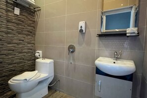 Une salle de bain équipée de toilettes, d’un lavabo et d’un distributeur de savon.