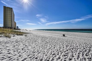 Ein Strand mit einem Hochhaus und blauem Himmel.