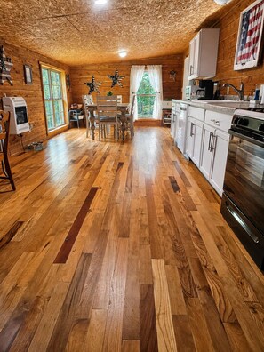 A spacious kitchen with wooden floors, white cabinets, and a large stove.