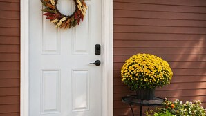 A white door with a wreath, a yellow flower pot, and a green plant on a wooden porch. - Secluded • Table Rock Lake Cabin • Near Branson (Green Forest)