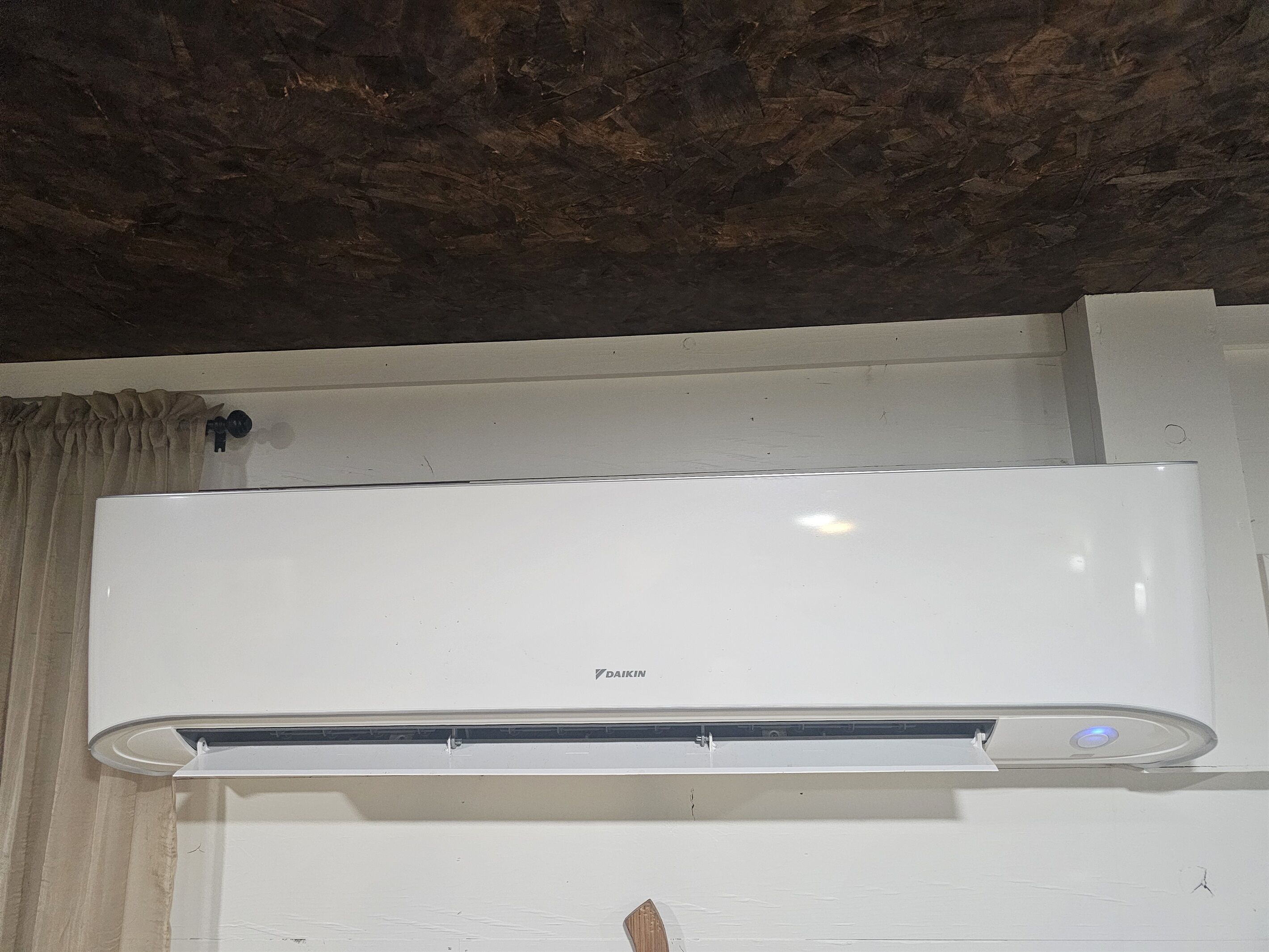 A white air conditioning unit mounted on a wall with a visible brand name.