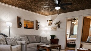 A living room with a sofa, coffee table, and a ceiling fan. - Secluded • Table Rock Lake Cabin • Near Branson (Green Forest)