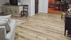 A living room with a wooden floor, a white sofa, a TV on a cabinet, and a door leading to a dining area with wooden chairs. - Secluded • Table Rock Lake Cabin • Near Branson (Green Forest)