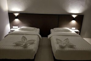 Two twin beds with white linens and a dark headboard, each with a bedside table and lamp. - Luna Guesthouse (Semporna)