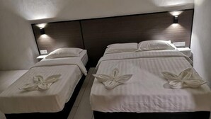 Two twin beds with white linens and floral bedspreads, a dark headboard, and wall-mounted lighting. - Luna Guesthouse (Semporna)